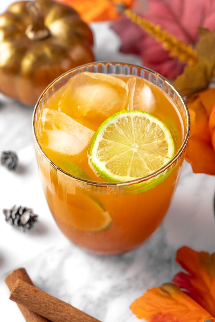 an orange drink in a glass with lemon and cinnamon garnish on the side