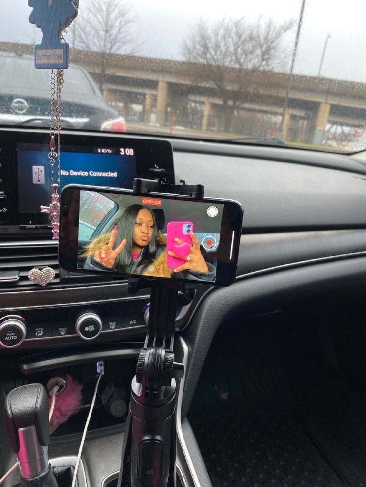 a cell phone mounted to the dash of a car with a woman on it's screen