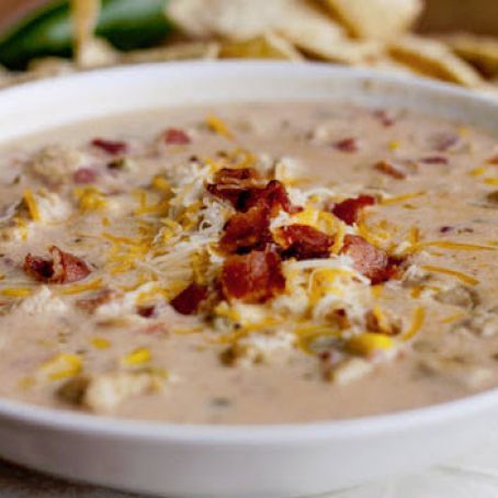 a white bowl filled with potato soup and bacon on top of it next to tortilla chips