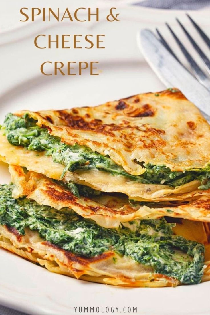 spinach and cheese crepe on a white plate with a fork next to it