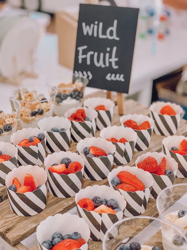 many small cups filled with fruit on top of a wooden table next to a sign that says wild fruit