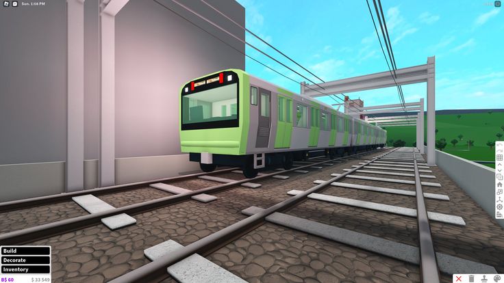 a green train traveling down tracks next to a building