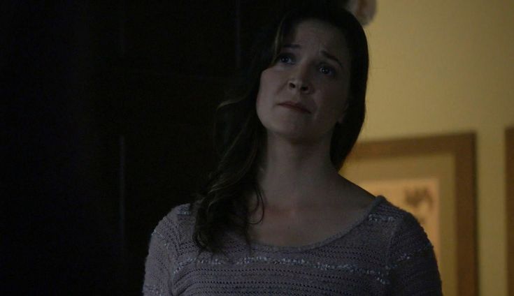 a woman standing in a dark room with her eyes closed and looking off to the side