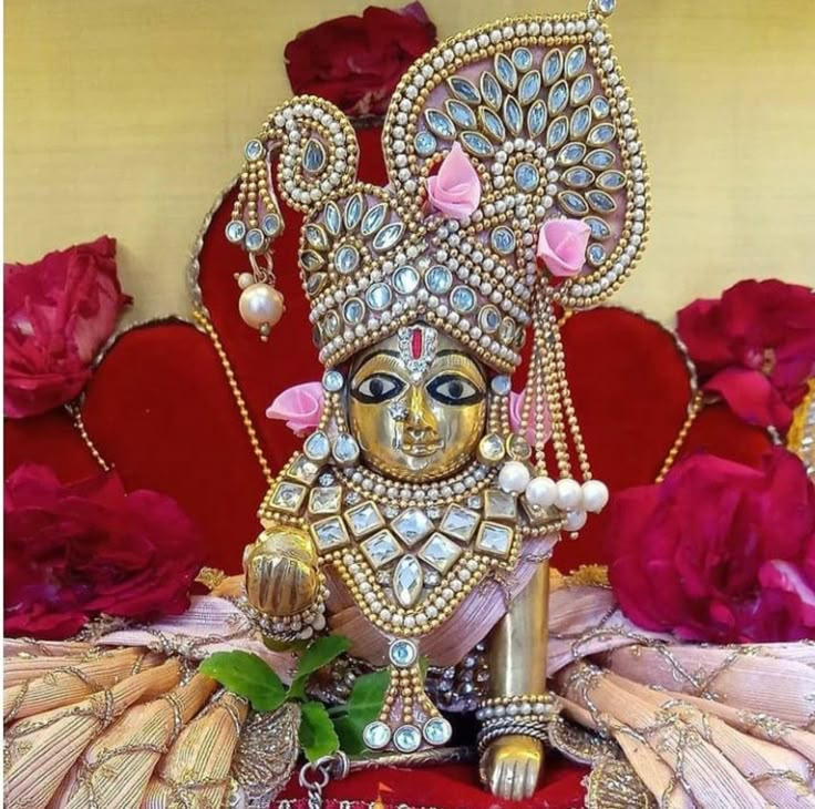 the statue is adorned with jewels and pearls on it's head, surrounded by red roses