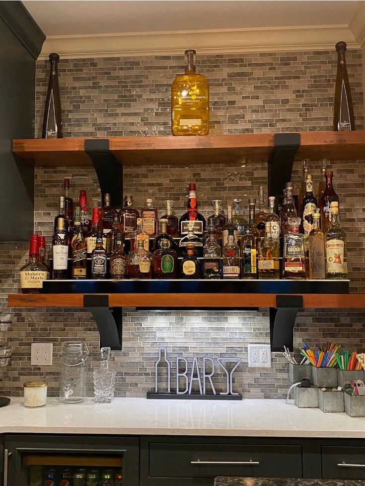 the shelves are filled with liquor bottles and glasses on top of them in a kitchen