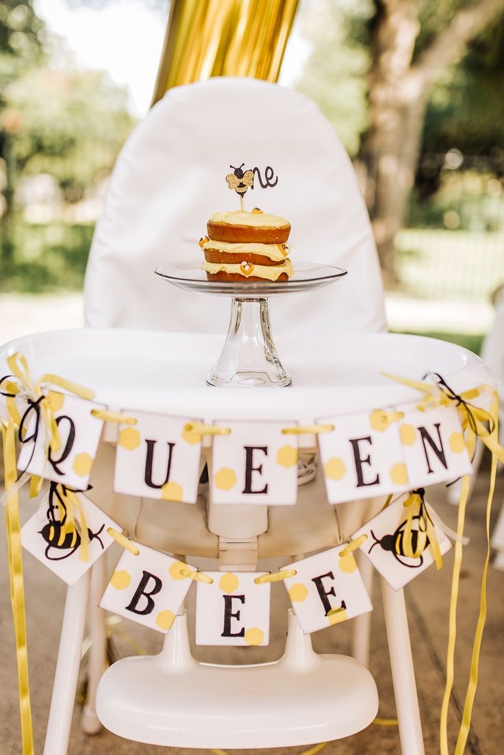 a table topped with a piece of cake on top of a white chair covered in yellow ribbon