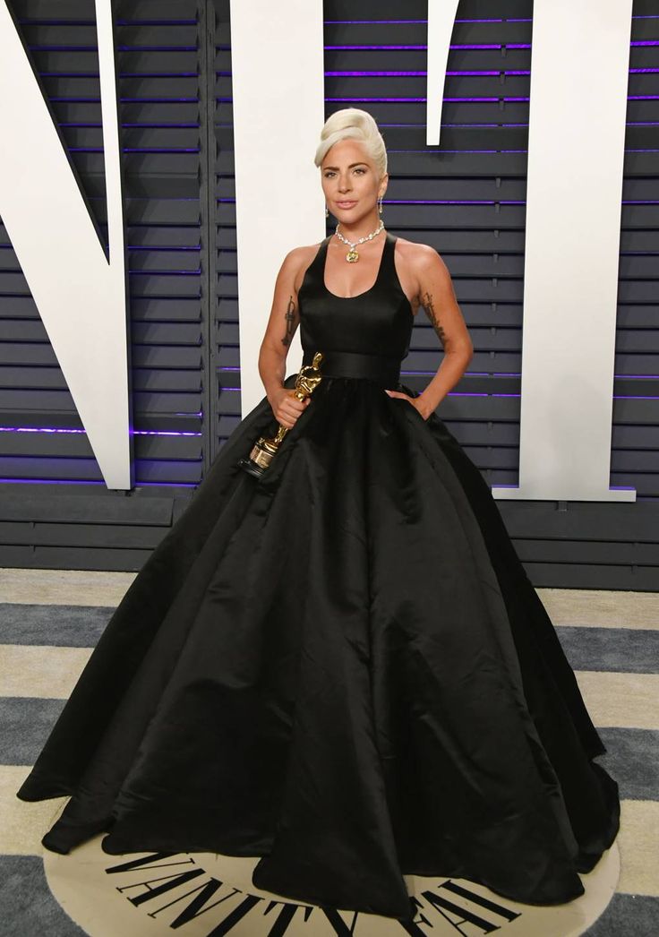 a woman in a black dress posing for the camera with her hands on her hips