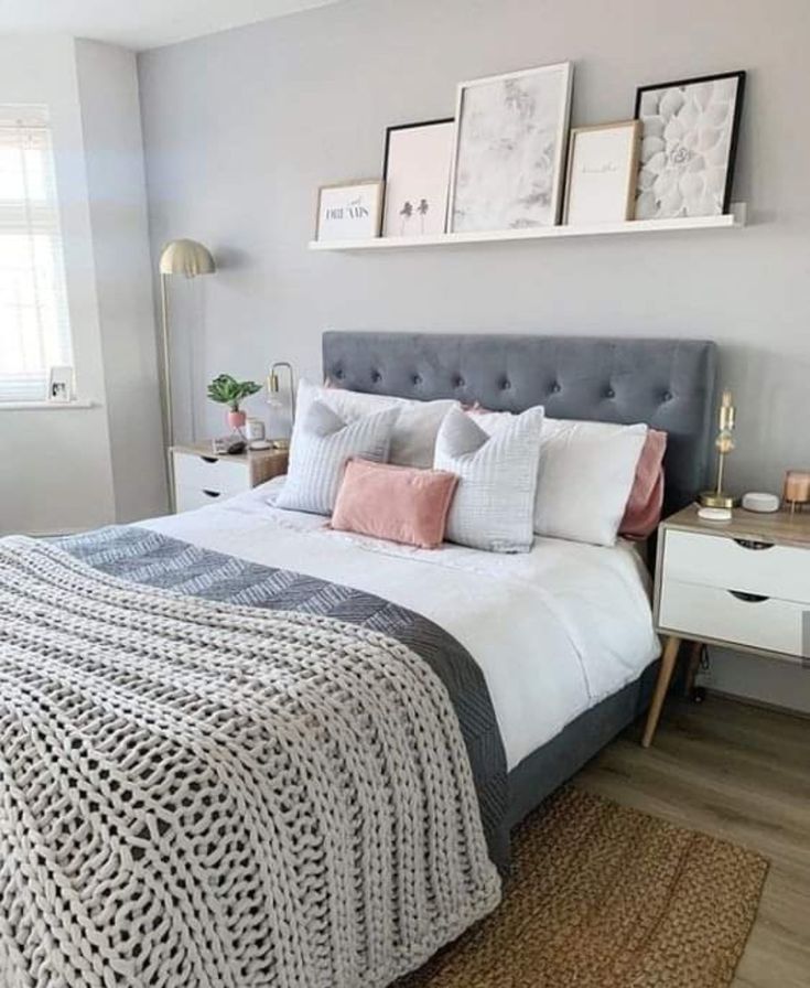 a bedroom with gray walls, white bedding and pink pillows on the headboard