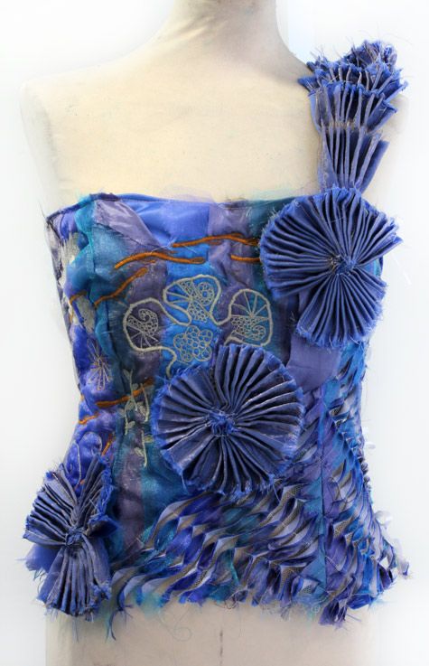 a mannequin with blue paper flowers on it's back and one piece of fabric attached to the torso