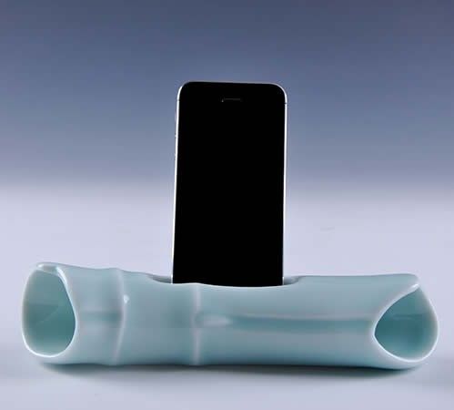 a cell phone is sitting on top of a white vase with a curved tube in the middle