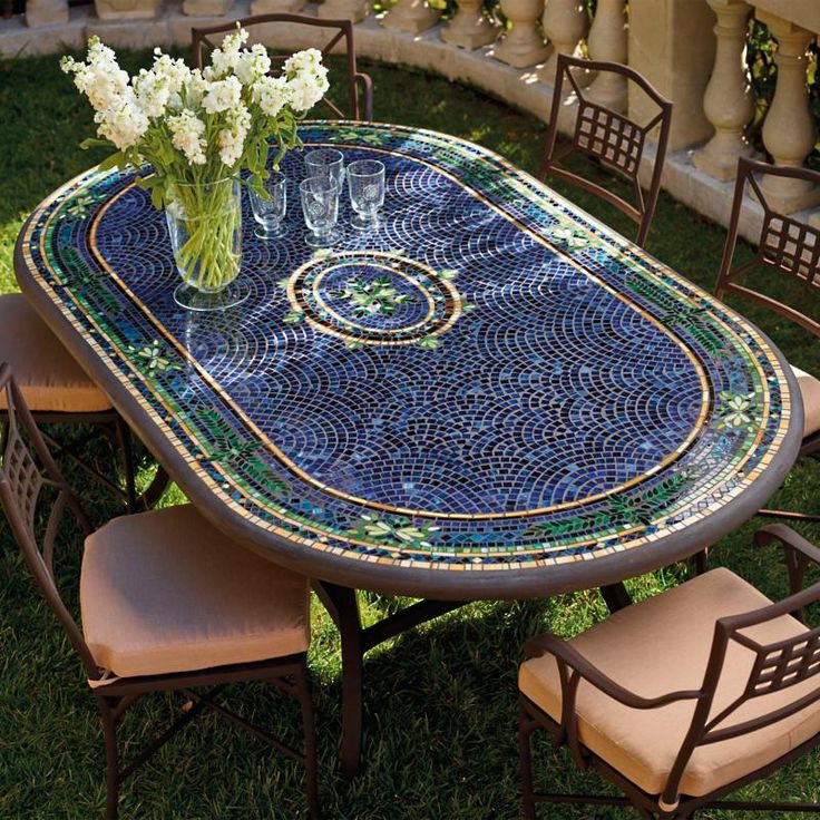 a mosaic table and chairs with flowers in vases on the top, sitting outside