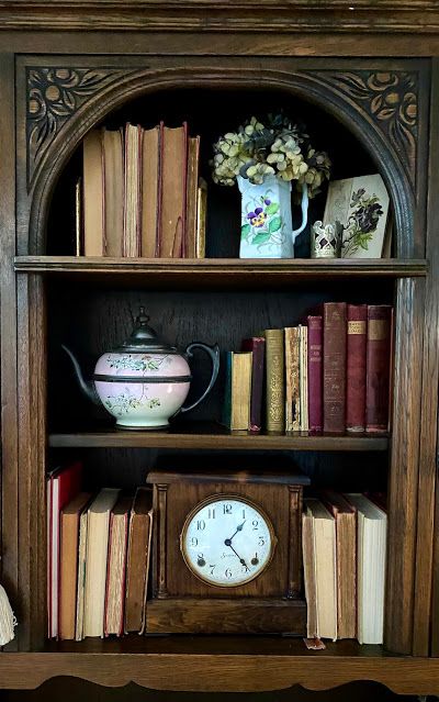 an old book shelf with books and a clock