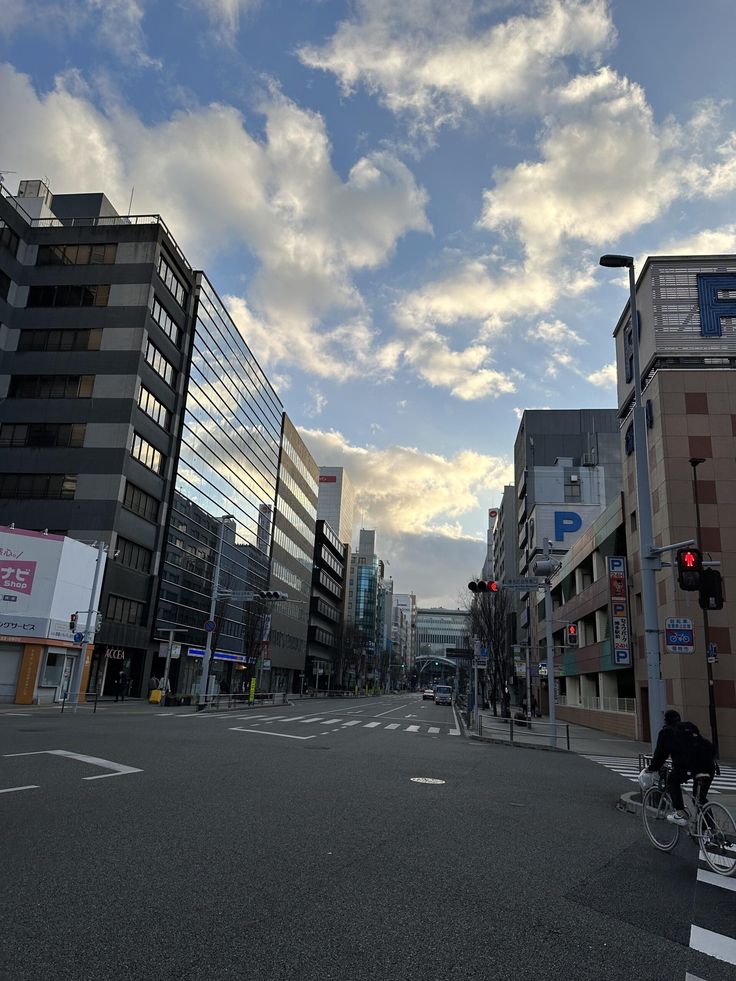 an empty city street with tall buildings on both sides and a red traffic light in the middle