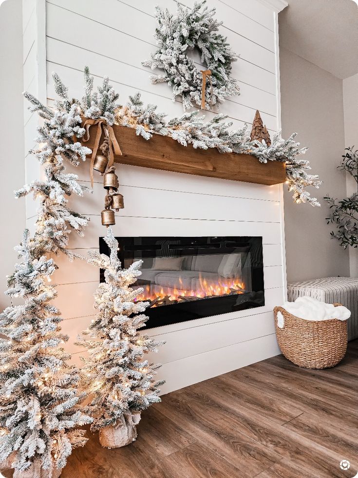 a fireplace with christmas decorations on the mantle, and two trees in front of it