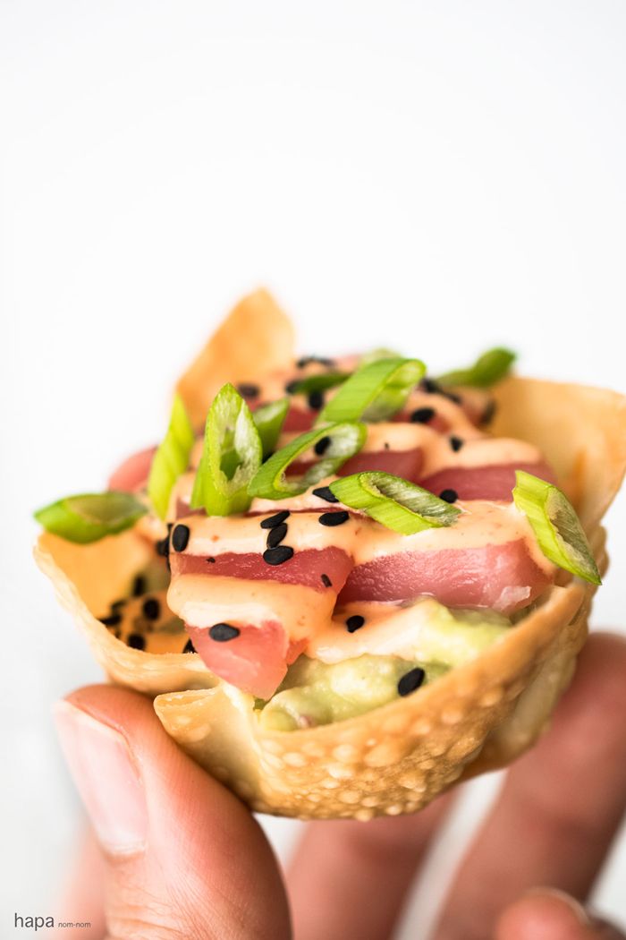 a person holding up a small pastry with fruit on it and sprinkles