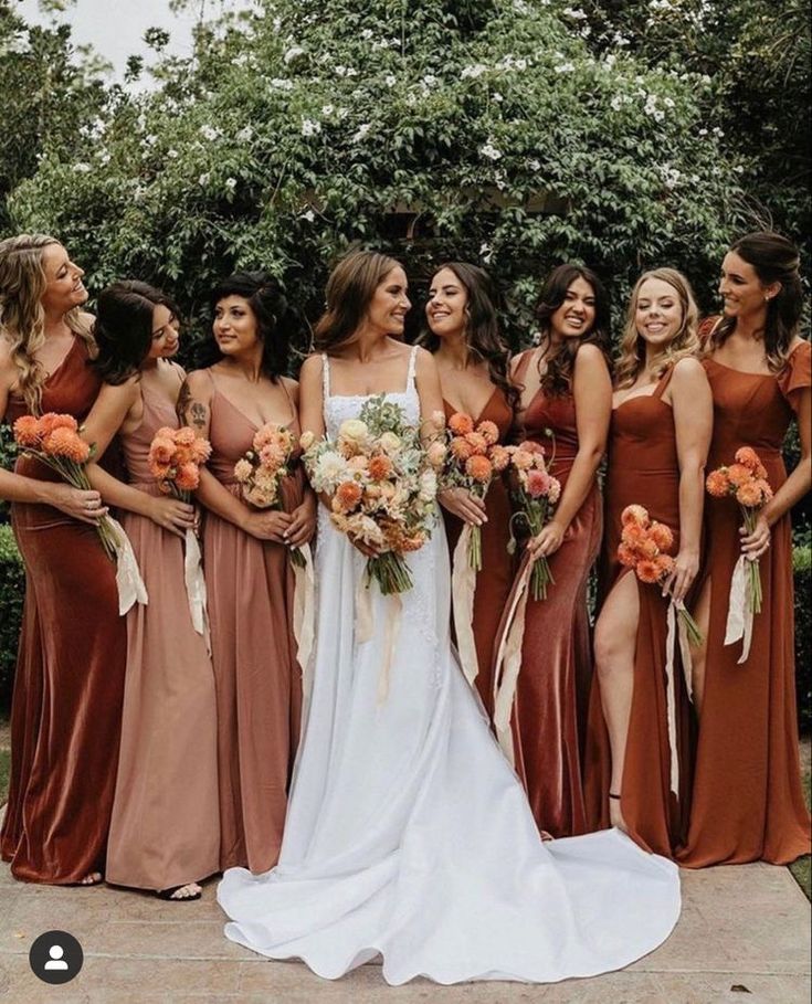 a group of women standing next to each other wearing dresses and holding bouquets in their hands