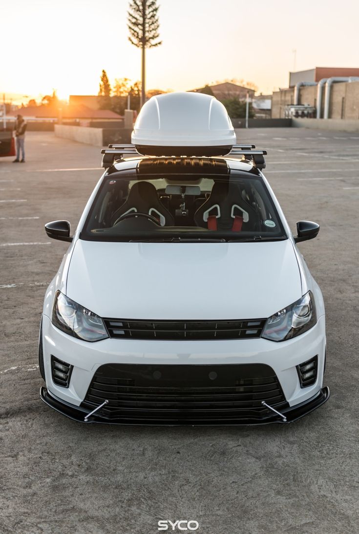 a white car parked in a parking lot with the sun shining on it's roof