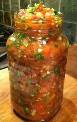 a jar filled with lots of food sitting on top of a wooden table next to a stove