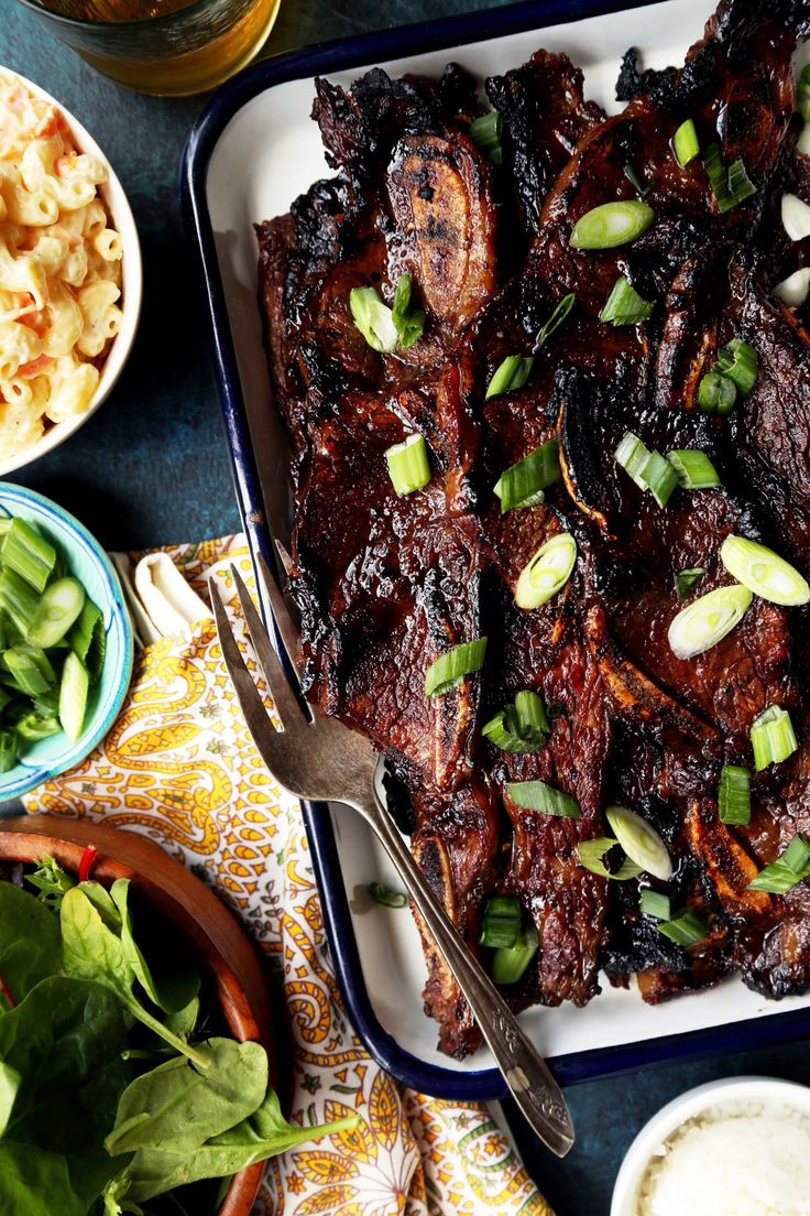 a platter filled with meat and vegetables on top of a table next to other dishes