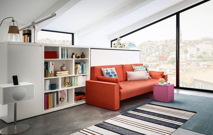 an orange couch sitting in front of a book shelf filled with books and other items