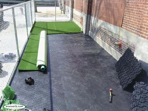 an indoor batting cage with artificial turf and baseball bats on the ground next to it