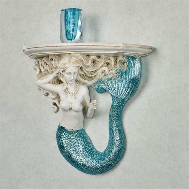 a white and blue shelf with a mermaid figurine on it's side