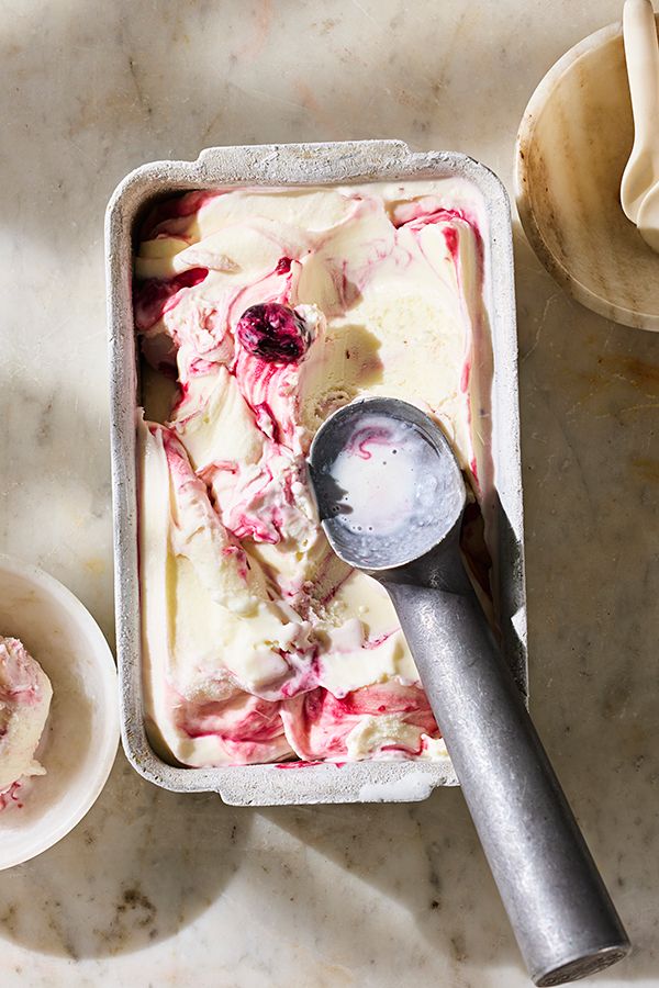 an ice cream dish with raspberries in it and a spoon next to it