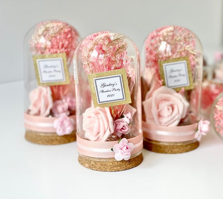 pink flowers in glass jars with labels on them