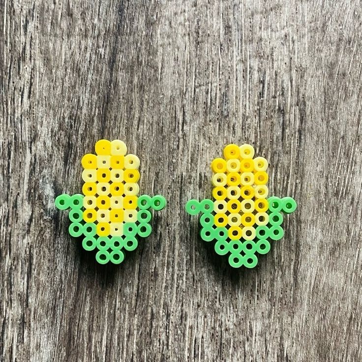 two green and yellow beads sitting on top of a wooden table next to each other