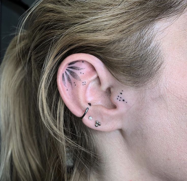 a woman's ear with black and white stars on it, behind her ear