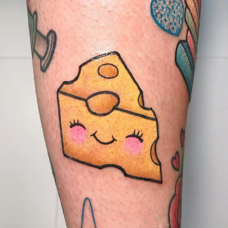 a tattoo with a piece of cheese on it's leg and other items around it