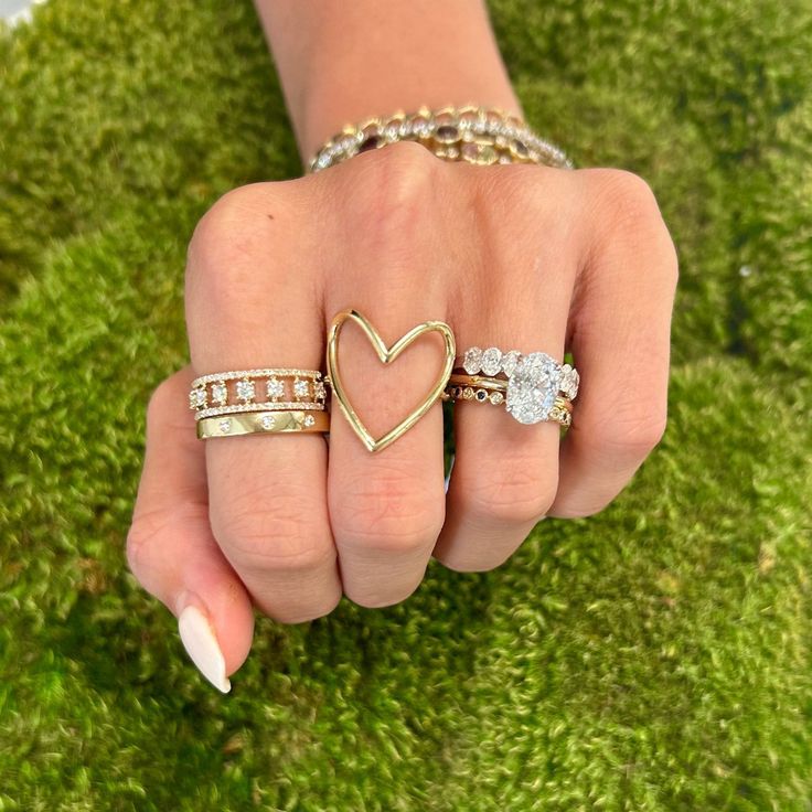 a woman's hand with three rings on it and a heart shaped diamond in the middle