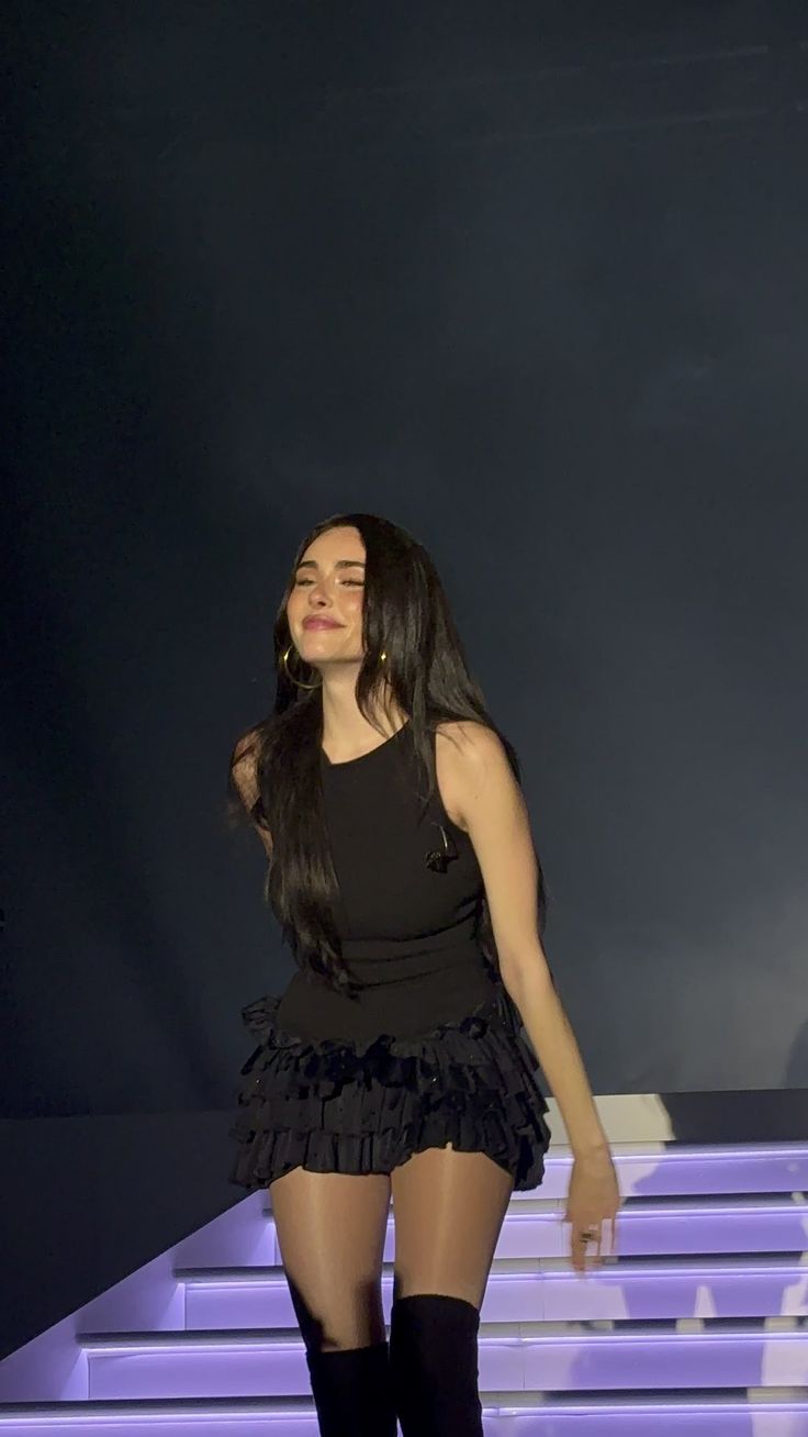 a woman in black dress and thigh high boots on stage