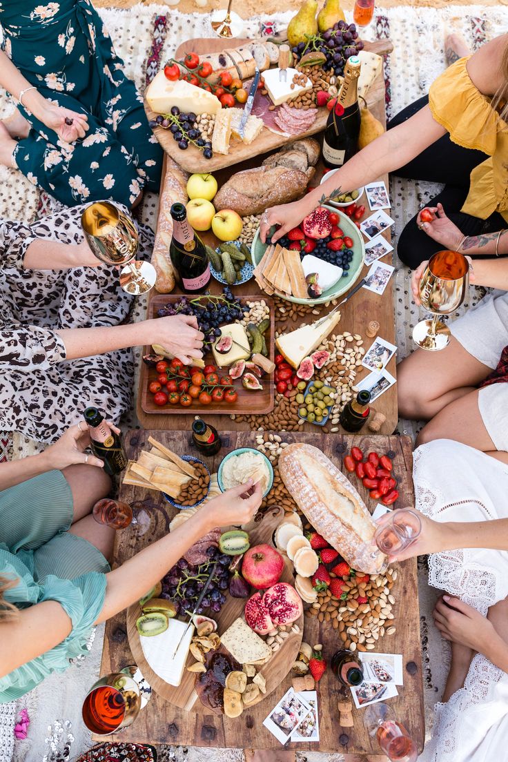 several people sitting around a table with food and drinks on it, all holding wine glasses