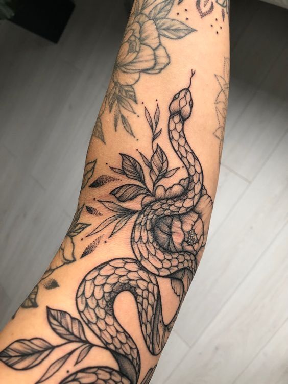 a person with a tattoo on their arm that has a snake and flowers on it