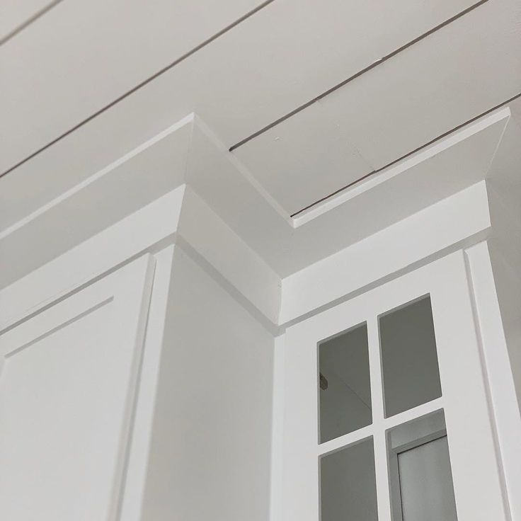 the corner of a room with white painted walls and trimmings on the ceiling