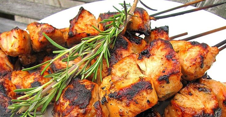 chicken skewers on a plate with rosemary garnish