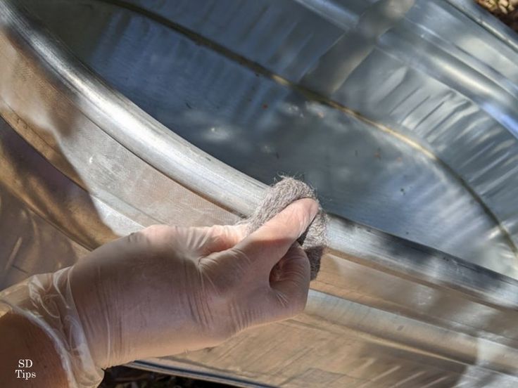 a hand holding something in front of a metal object