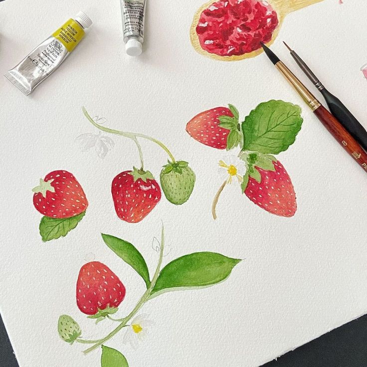 some strawberries are sitting on a table with paint and watercolors next to it