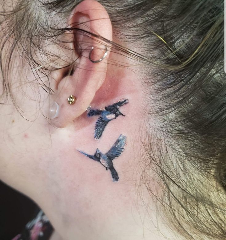 a woman's ear with two birds on it