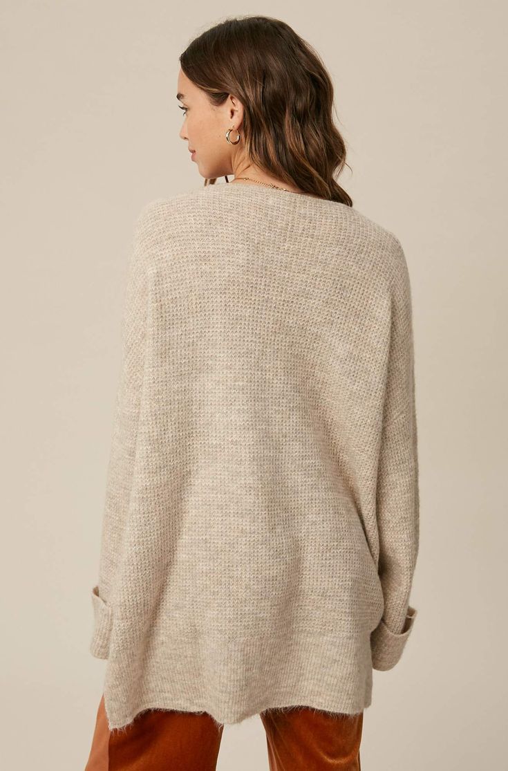 So chic and effortless, this slouchy, oversized tunic-style sweater features a v-neckline and dropped wide sleeves for added shape. -Available in Stone & Misty Blue -Waffle textured -V-neck -Oversized fit -Soft touch eyelash two tone yarn -Long sleeve with folded cuffs -Side slits -Ribbed on hem -Content: 74% Acrylic 22% Polyester 4% Lycra -Hand was cold/Line dry -Imported -Model is 5 8" 32-24-34 and wearing a size Small Oversized V-neck Sweater For Layering, Oversized Chic V-neck Sweater, Oversized V-neck Sweater For Fall, Oversized V-neck Sweater For Loungewear, Chic Oversized V-neck Sweater For Loungewear, Oversized V-neck Chic Sweater, Oversized Knit V-neck Sweater With Long Sleeves, Oversized Chic Sweater With Ribbed Neckline, Oversized V-neck Versatile Sweater