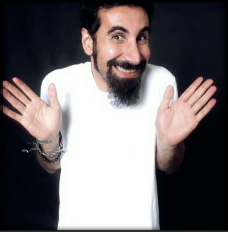 a man with a beard and white shirt holding his hands up