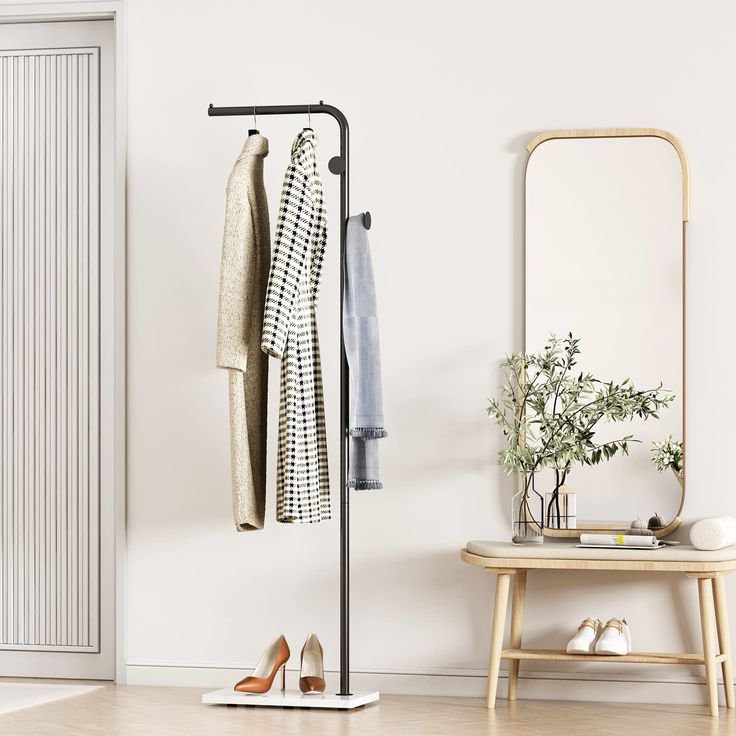 a coat rack with two coats hanging on it next to a mirror and wooden stool