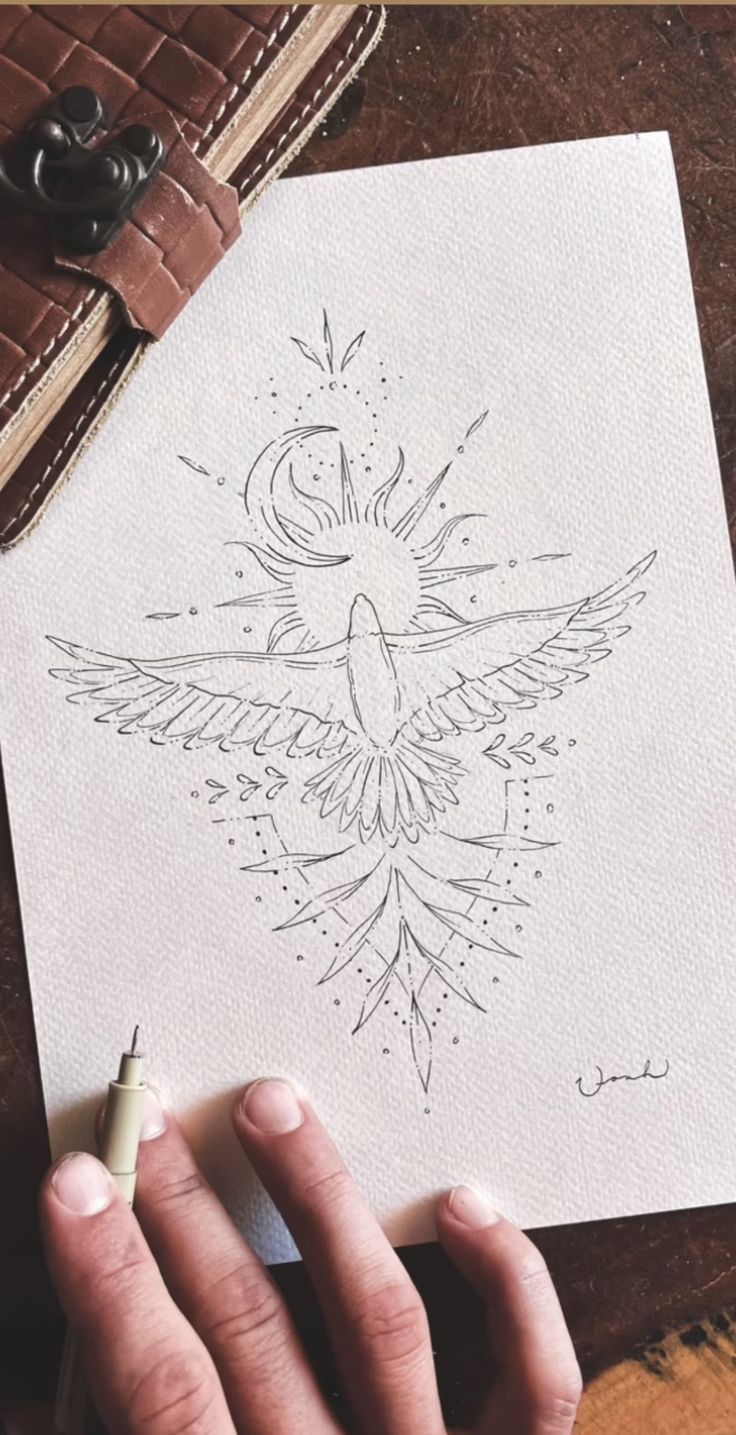 a person holding a pen and drawing something on paper with the image of a bird