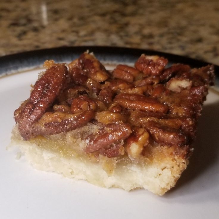 a piece of pecan pie sitting on top of a white plate