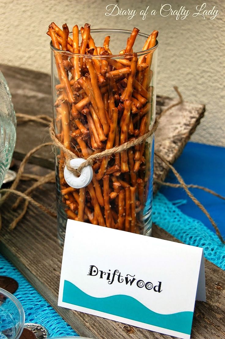 a jar filled with fries sitting on top of a wooden table next to a sign