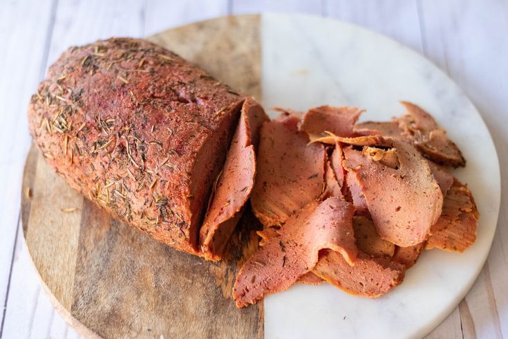 sliced meat sitting on top of a wooden cutting board