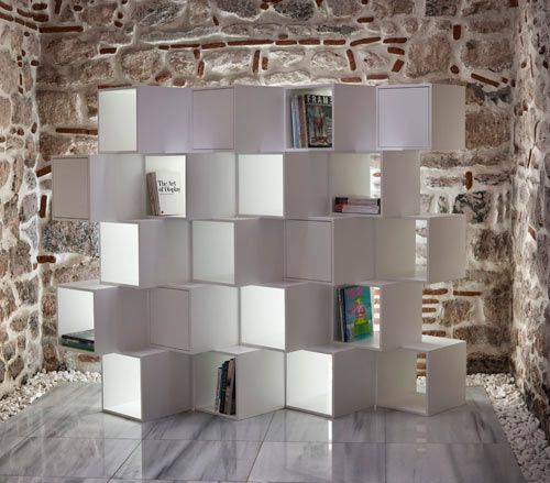 a book shelf made out of white cubes in an old stone room with brick walls