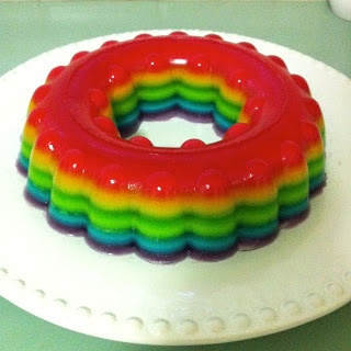 a rainbow colored ring cake on a white plate