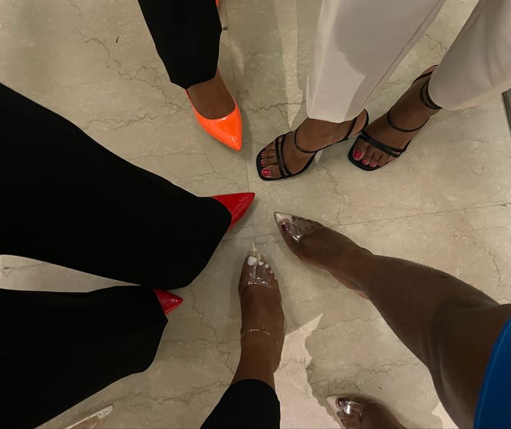 four women standing in a circle with their feet on the ground wearing high heeled shoes